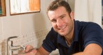 Plumber working on sink smiling