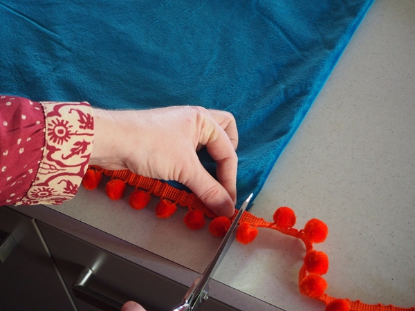 Measure the pom pom trimming against the edge of the cushion cover and cut accordingly