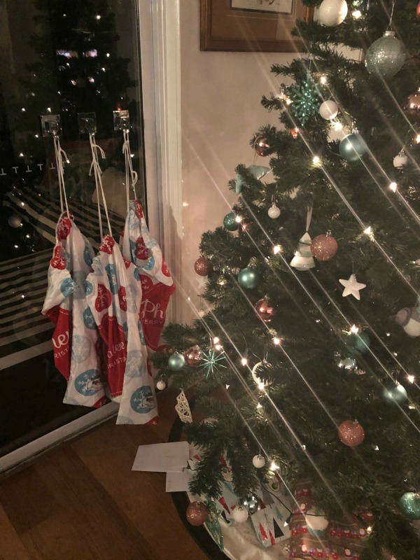 christmas lights on tree and stockings hung on window